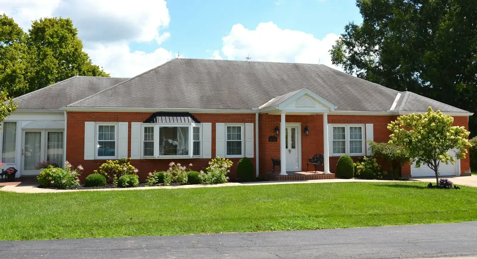 A red brick ranch house with white shutters
